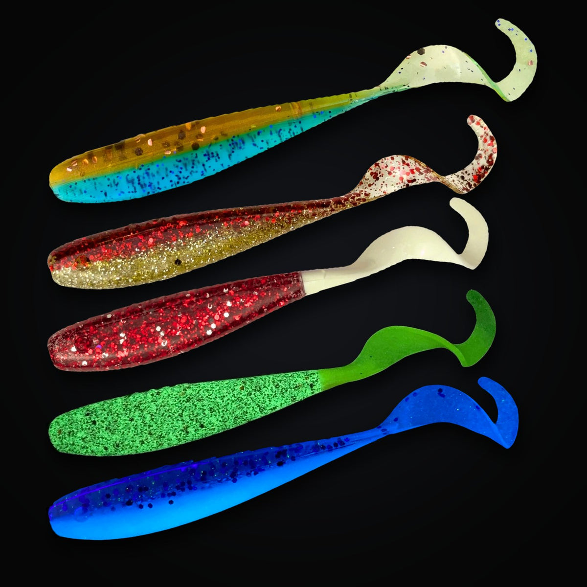 Five A.M. Fishing curly tail jerkshads on black: Blue Crab, Money and Blood Diamond, plus U.V. Rootbeer and Dragonfruit glowing